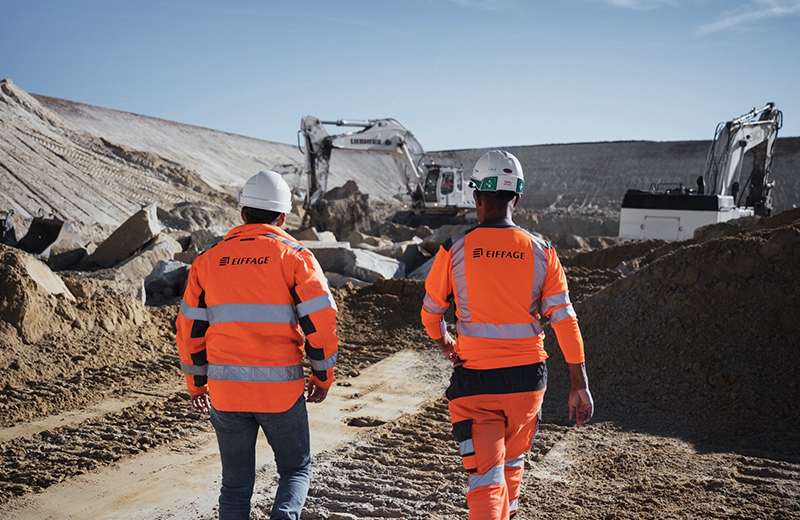 Deux collaborateurs Eiffage de dos à côté de pelleuteuses - Crédit photo : ©Atypix